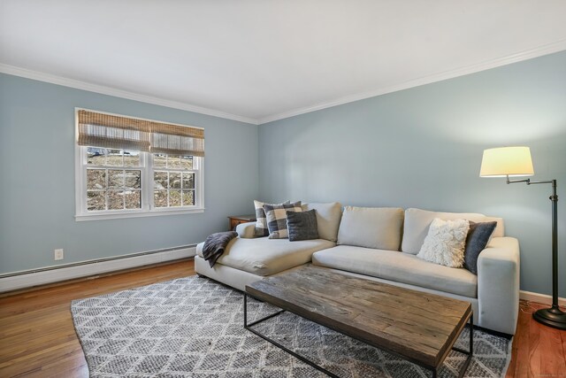 living area with a baseboard heating unit, crown molding, baseboards, and wood finished floors