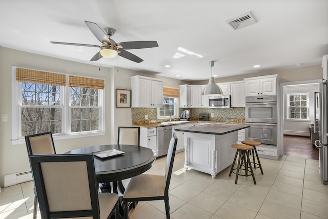 kitchen featuring stainless steel appliances, visible vents, backsplash, a center island, and dark countertops