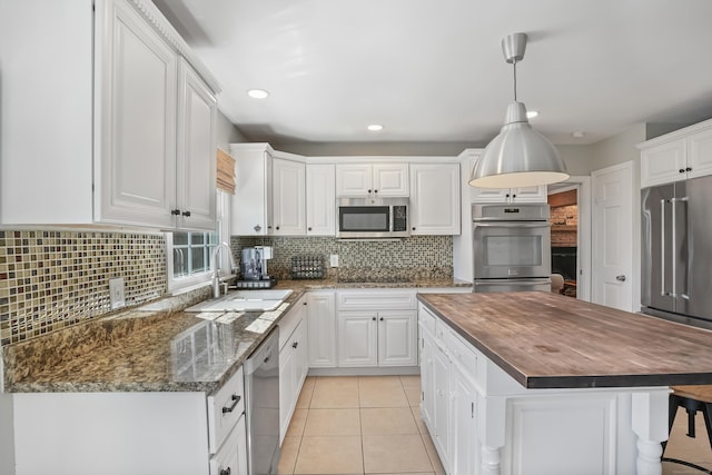 kitchen featuring light tile patterned floors, a center island, stainless steel appliances, wooden counters, and a sink