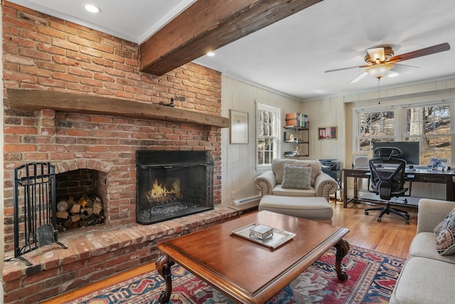 living room featuring a fireplace, a baseboard radiator, ceiling fan, beamed ceiling, and hardwood / wood-style flooring