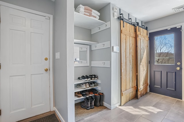 mudroom featuring a barn door, visible vents, and baseboards