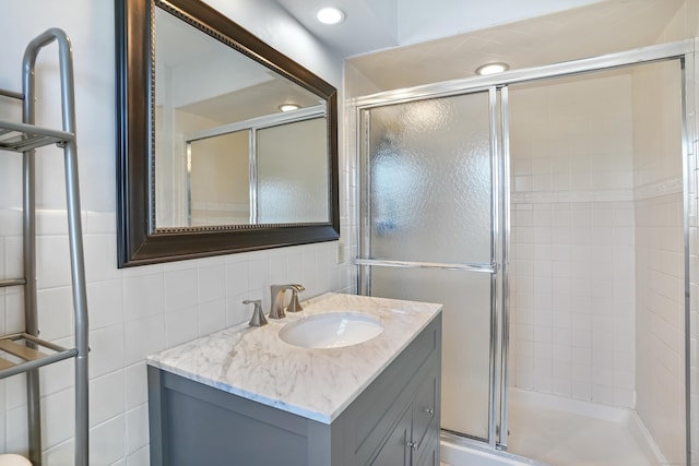 full bath with tile walls, vanity, a shower stall, backsplash, and recessed lighting