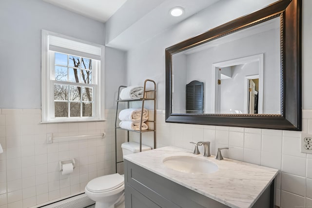 bathroom with toilet, a baseboard radiator, tile walls, and vanity