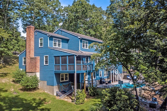 back of property featuring a chimney, a lawn, a sunroom, fence, and stairs