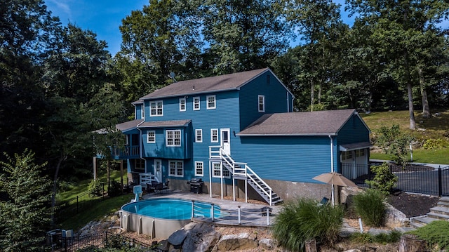 rear view of house with fence, stairway, and a fenced in pool