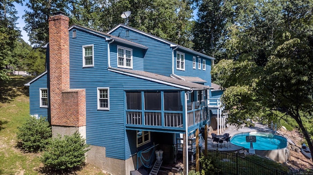 rear view of property featuring a fenced in pool, a sunroom, a fenced backyard, a chimney, and a patio area