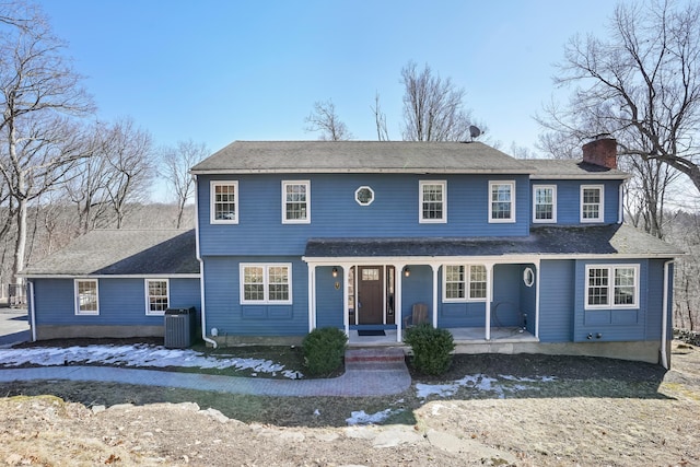 view of front of house with a porch, a chimney, and central AC unit