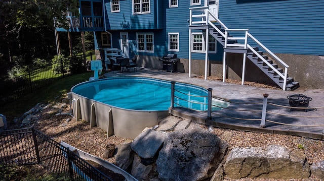 view of swimming pool featuring an outdoor fire pit, a fenced backyard, area for grilling, stairway, and a fenced in pool