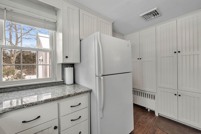 kitchen featuring white refrigerator, dark hardwood / wood-style flooring, radiator, light stone countertops, and white cabinets