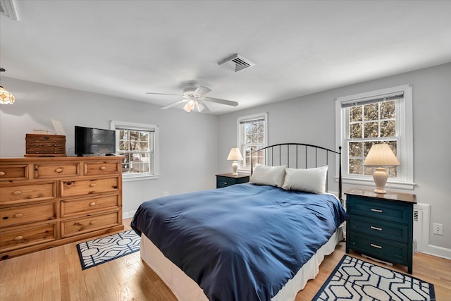 bedroom with multiple windows, light hardwood / wood-style floors, and ceiling fan