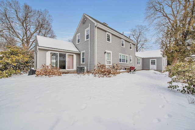 snow covered back of property featuring central AC unit