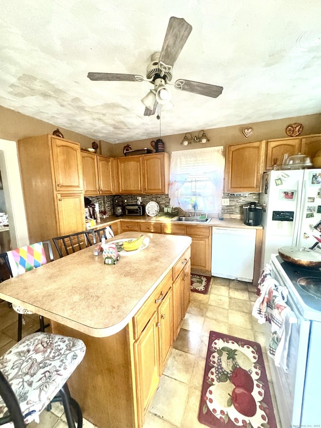 kitchen with sink, tasteful backsplash, a center island, ceiling fan, and white appliances