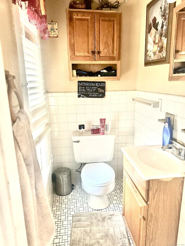 bathroom featuring vanity, toilet, and tile walls