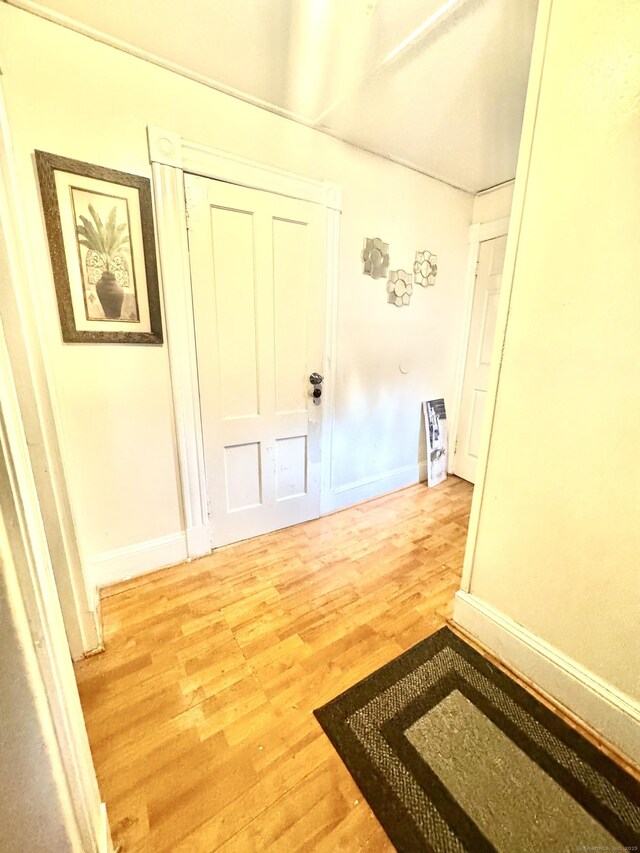 hall with light wood-style flooring and baseboards