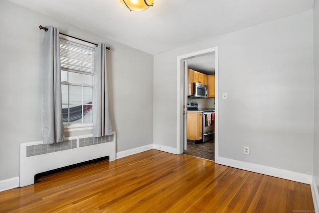 spare room with dark wood-type flooring and radiator heating unit