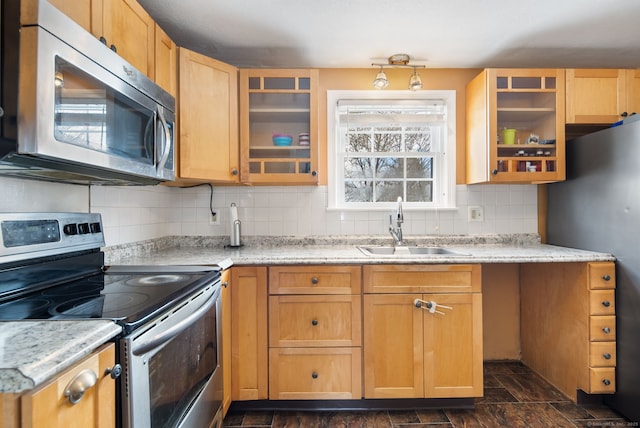 kitchen with appliances with stainless steel finishes, light stone countertops, sink, and backsplash