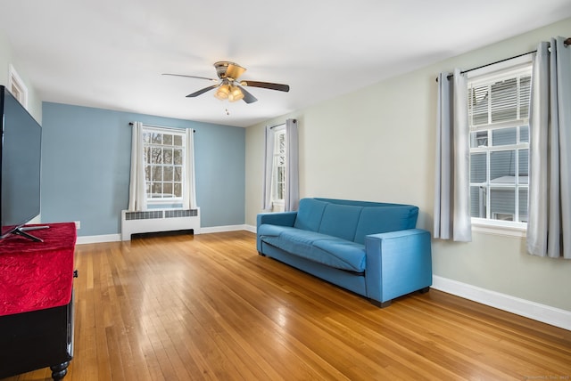 living area featuring radiator, hardwood / wood-style floors, and ceiling fan