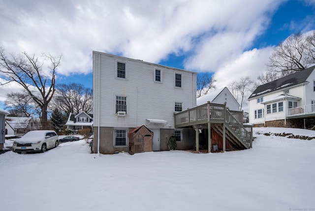 snow covered back of property with a wooden deck