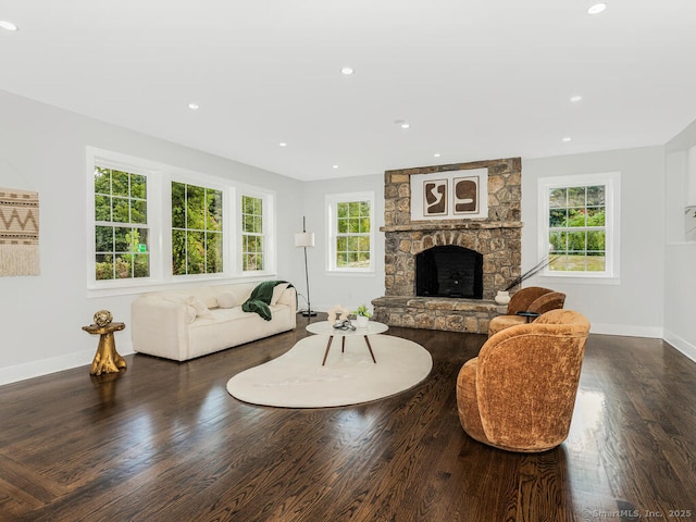 living room with dark wood-type flooring, a wealth of natural light, and a fireplace