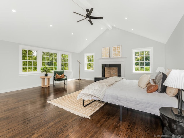 bedroom featuring multiple windows, dark wood-type flooring, ceiling fan, and beamed ceiling