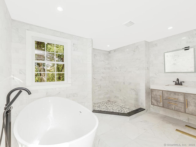 bathroom featuring vanity, independent shower and bath, and tile walls