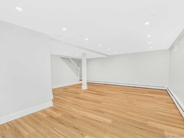 basement with light hardwood / wood-style flooring and baseboard heating