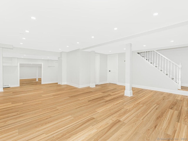 basement with a baseboard heating unit and light hardwood / wood-style floors