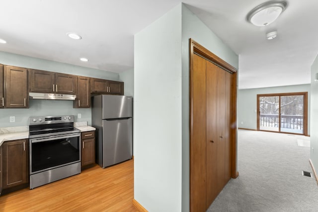 kitchen with light carpet, dark brown cabinets, and stainless steel appliances