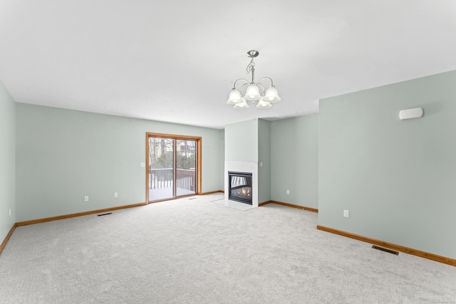 unfurnished living room featuring a tile fireplace, light carpet, and an inviting chandelier