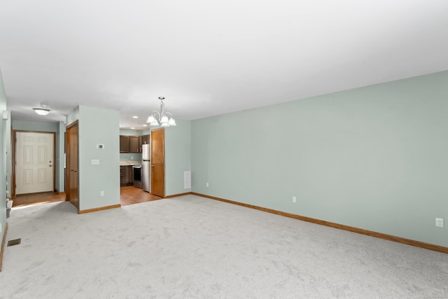 unfurnished living room featuring light carpet and an inviting chandelier