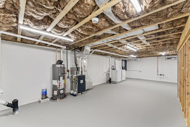 basement with heating unit, gas water heater, and independent washer and dryer