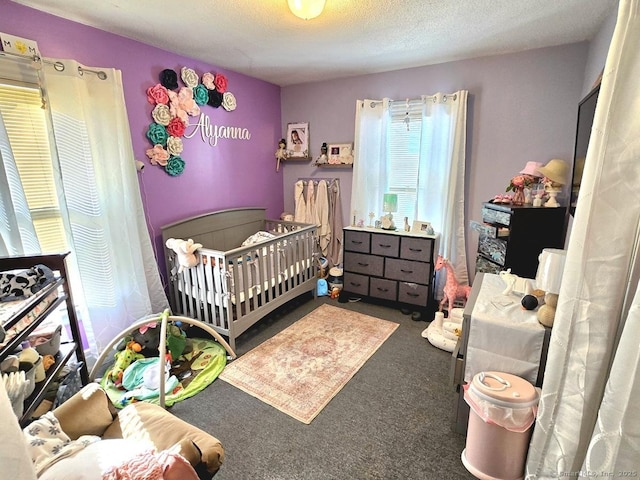 carpeted bedroom featuring a crib and a textured ceiling