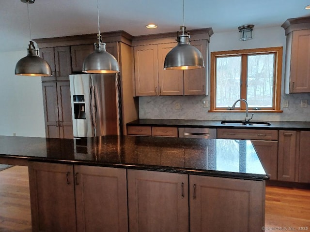 kitchen with decorative light fixtures, sink, backsplash, dark stone counters, and stainless steel appliances