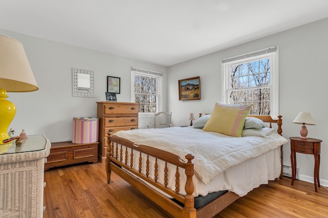 bedroom with a baseboard heating unit and wood finished floors