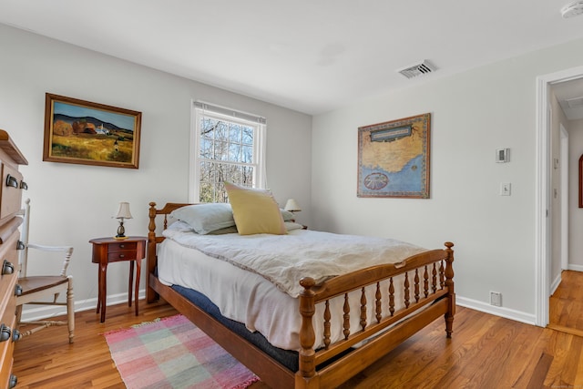 bedroom with visible vents, baseboards, and wood finished floors