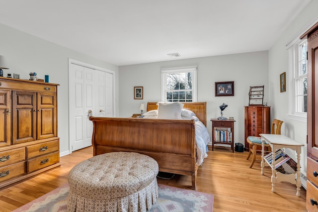 bedroom with light wood-style flooring, visible vents, and a closet