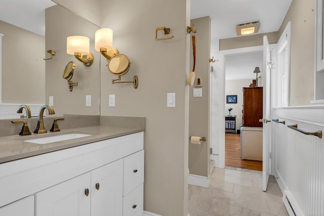 bathroom with marble finish floor, a baseboard heating unit, and vanity