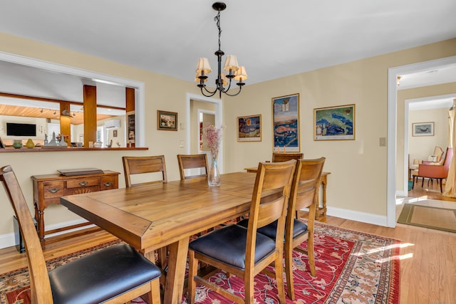 dining area featuring baseboards, a chandelier, and wood finished floors