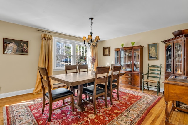 dining room featuring a chandelier, light wood-style flooring, and baseboards