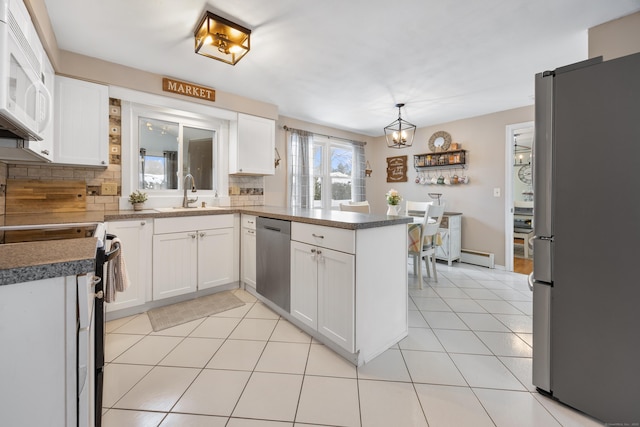 kitchen with white cabinetry, sink, stainless steel appliances, and kitchen peninsula