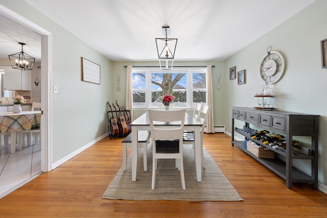 dining space featuring a notable chandelier, light hardwood / wood-style floors, and baseboard heating