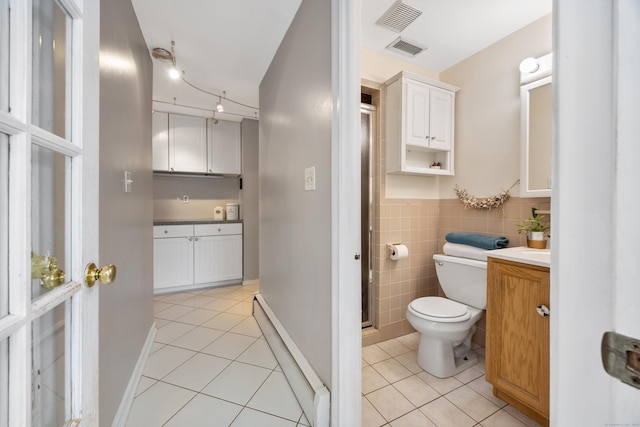 bathroom with tile walls, tile patterned flooring, vanity, baseboard heating, and toilet