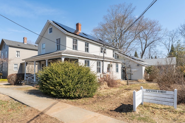 view of side of home featuring roof mounted solar panels and a chimney