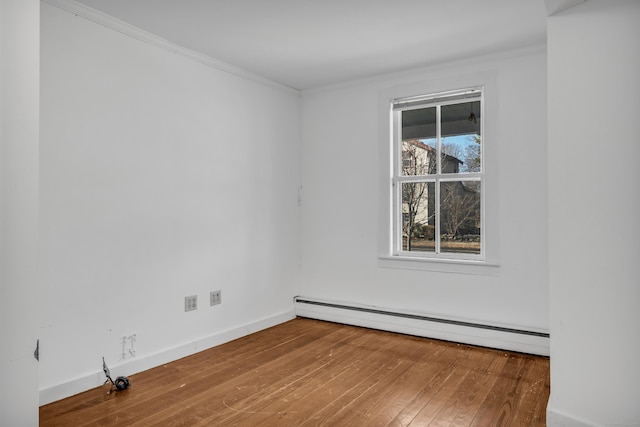 unfurnished room featuring a baseboard heating unit, hardwood / wood-style flooring, baseboards, and ornamental molding