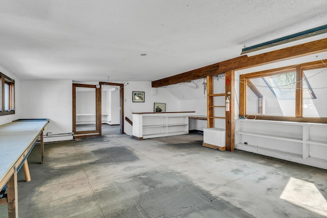 miscellaneous room with a baseboard heating unit, unfinished concrete flooring, and a textured ceiling