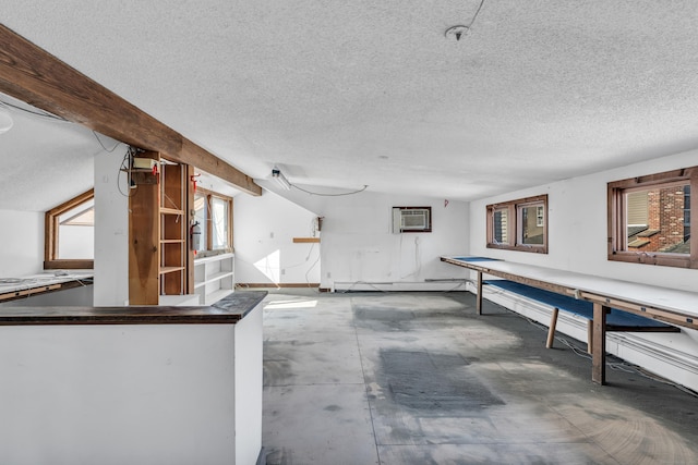 interior space with concrete floors, baseboard heating, an AC wall unit, and a textured ceiling