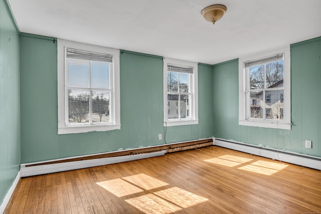 spare room featuring a baseboard heating unit and hardwood / wood-style flooring