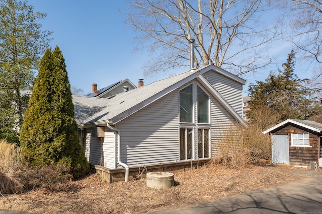 view of side of home with roof with shingles