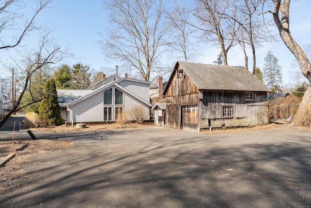 view of side of property with an outbuilding, a barn, and aphalt driveway