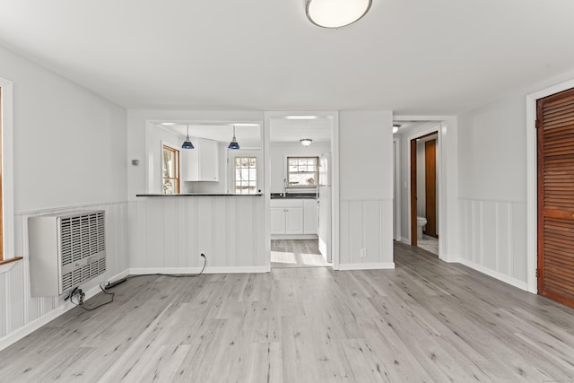 unfurnished living room featuring heating unit and light wood-type flooring